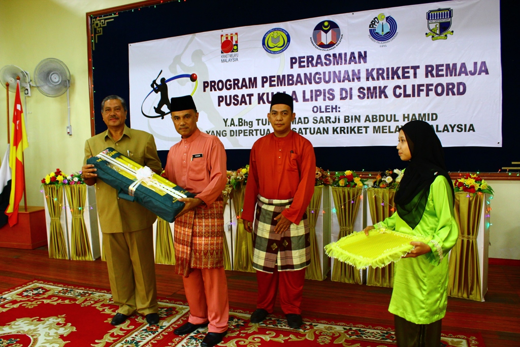 AHMAD SARJI menyampaikan antara pealatan kriket kepada Pengetua Sekolah Menengah Kebangsaan Clifford, Kuala Lipis, Haidzir Hussin (dua dari kiri) sewaktu pelancaran pusat ke-18 Program Pembangunan Kriket Remaja baru-baru ini.